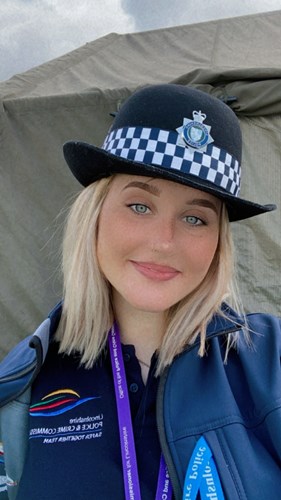 A smiling Maisie in the sunshine wearing a Lincolnshire Police helmet on her head